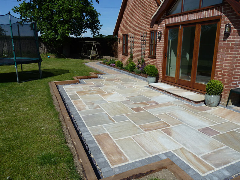Gary Cooper Paving Sandstone patio edged with charcoal border and